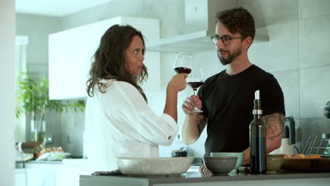Happy-young-couple-drinking-red-wine-at-kitchen